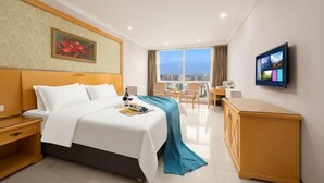 Habitación de hotel con cama, escritorio, televisión y vistas a la ciudad.