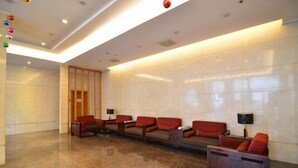 A lobby with a long reception desk, several red upholstered sofas, and a polished marble floor. - Jinyuwan Hotel (Dalian)