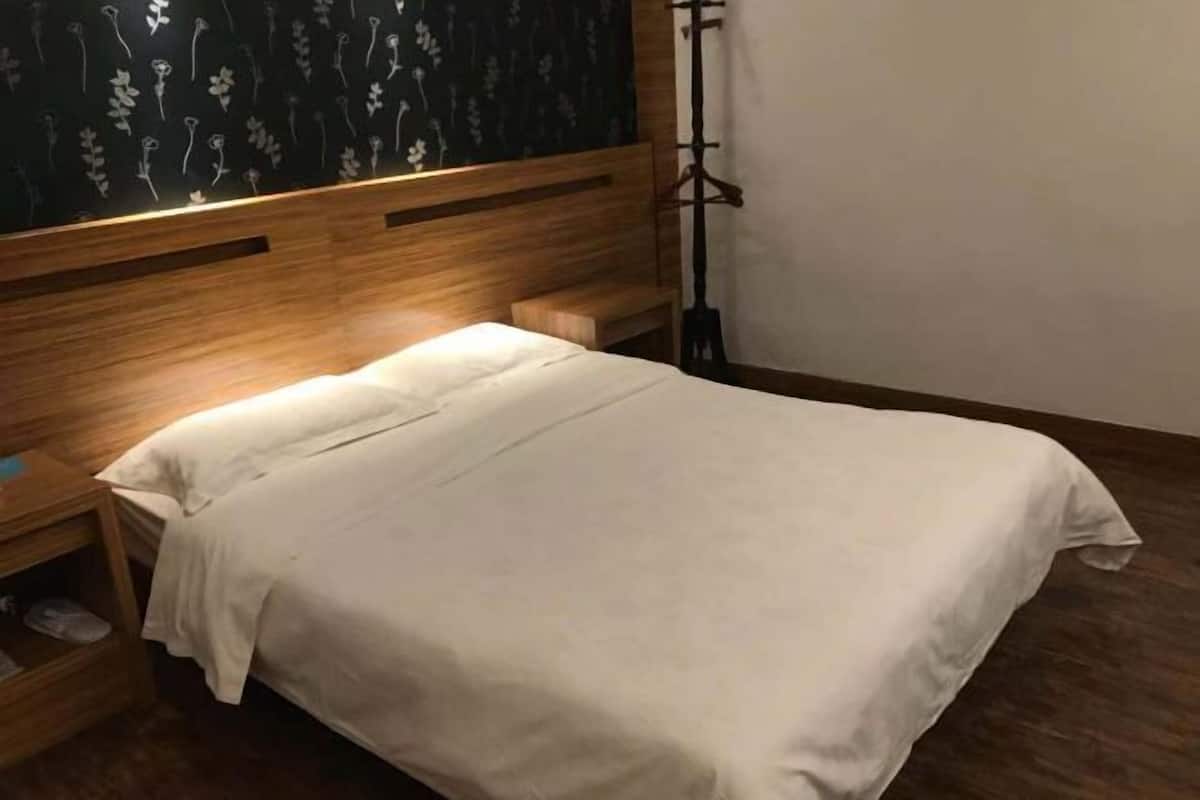 A neatly made bed with a wooden headboard and a nightstand with a shoe rack.