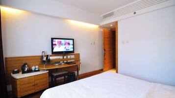 Una habitación de hotel con una cama, un escritorio con televisor y un armario de madera.
