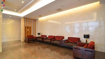A lobby with a reception desk, seating area, and a wooden door.