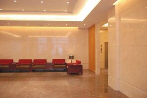 A lobby with a reception desk, a seating area with chairs, and a marble floor. - Jinyuwan Hotel (Dalian)