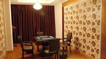 A room with a table and chairs, a chandelier, and patterned wallpaper.