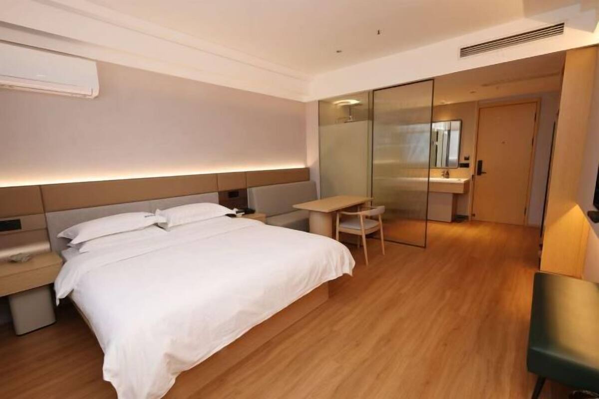 A hotel room with a bed, bedside table, desk, chair, and a mirror.