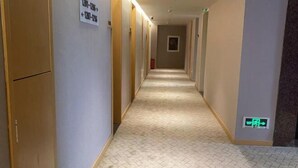 A hotel hallway with carpeted floors, wooden doors, and a sign indicating room directions. - Ruihao Hotel (Pingyang)