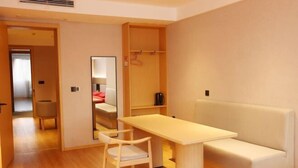 A modern hotel room with a wooden floor, a white sofa, a small table, and a mirror. - Ruihao Hotel (Pingyang)