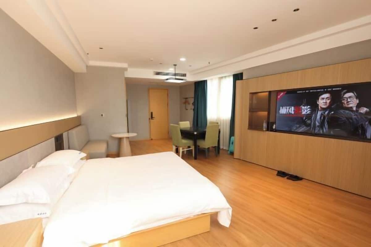 A hotel room with a bed, a TV, a small table, and a chair.