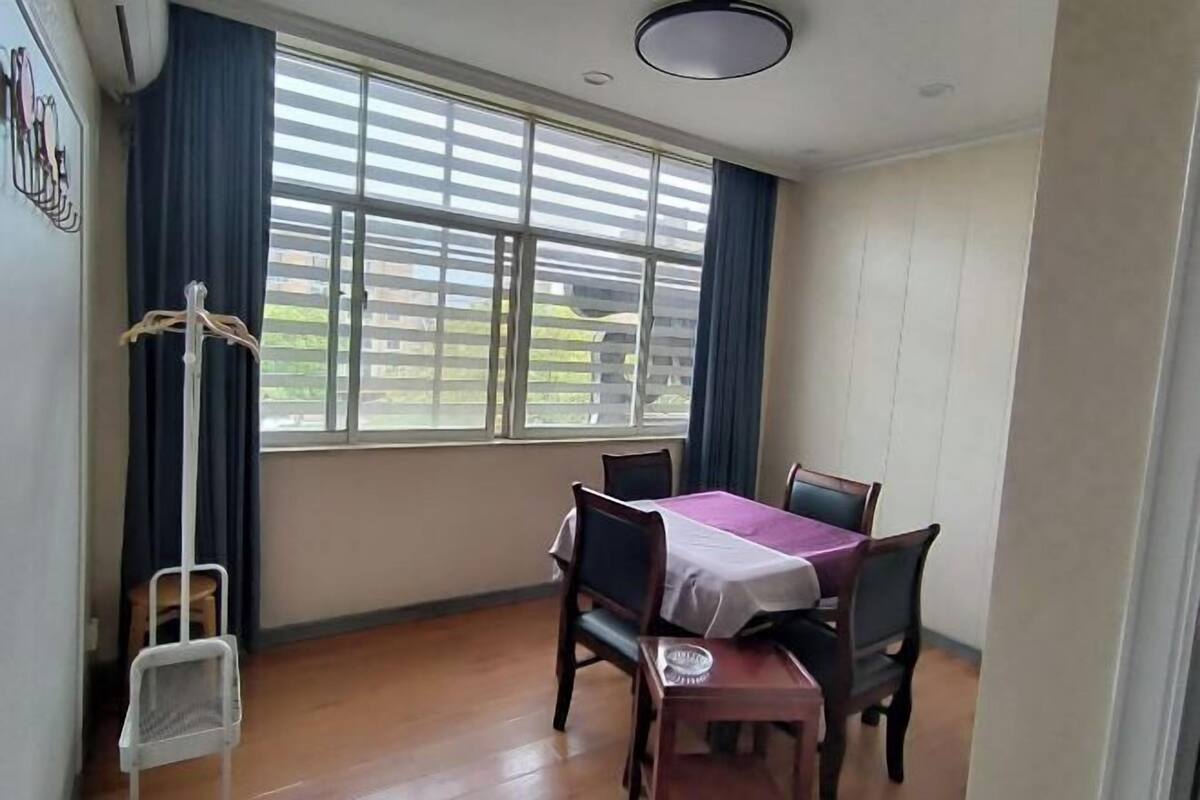 A dining area with a table set for four, a chair, a small table, and a coat rack.
