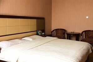 Une chambre dâhĂŽtel avec un grand lit, deux chaises, une petite table et une table de chevet.