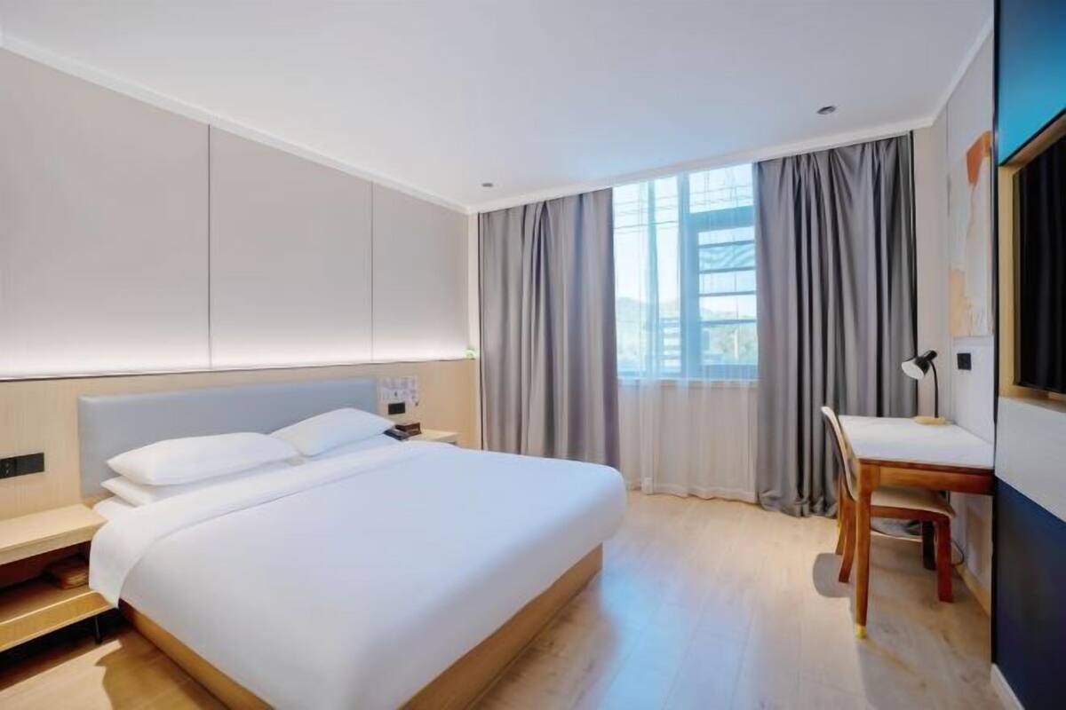 A modern hotel room with a large bed, a desk, and a chair.