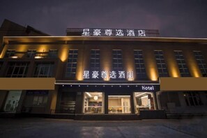 Un hotel con fachada moderna, señalización iluminada y una entrada acogedora.