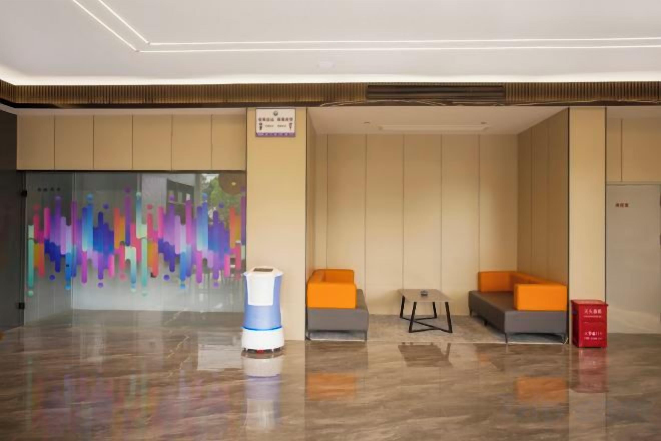 A lobby with a reception desk, seating area, and a colorful abstract wall.