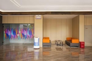 Un vestíbulo con mostrador de recepción, zona de estar y una pared abstracta y colorida.