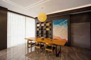 Un comedor moderno con una mesa y sillas de madera, una estantería y un cuadro abstracto grande en la pared.
