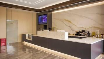 A hotel reception area with a marble counter, a television screen, and a modern design.