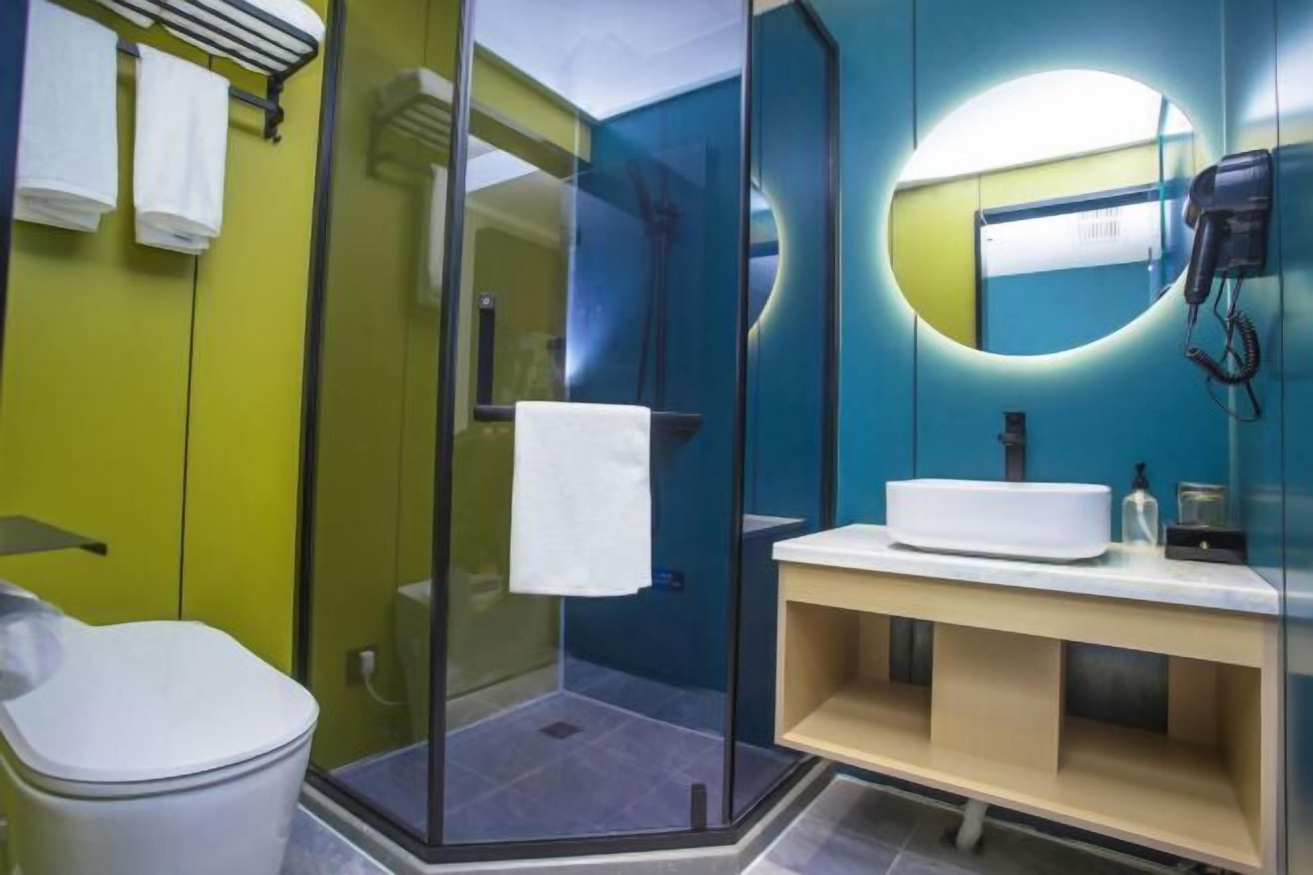 Een moderne badkamer met een douchecabine van glas, een wit toilet en een wastafelmeubel met een wastafel.
