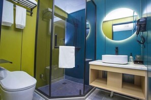 Un baño moderno con cabina de ducha de vidrio, inodoro blanco y tocador con lavabo.