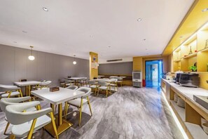 A modern hotel dining area with multiple tables and chairs, a kitchen area, and a view of the street. - Xinghao Zunxu Hotel (Rui'an)