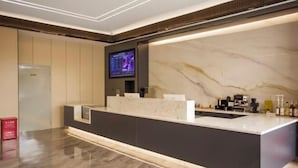 A modern reception area with a marble counter, a digital screen, and a clean, polished floor.