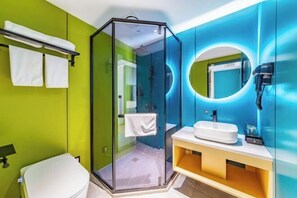 Un baño moderno con ducha de vidrio, lavamanos blanco y espejo con luz circular.