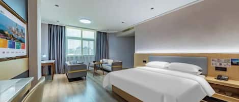 A hotel room with a large bed, a desk, a chair, and a window with curtains.