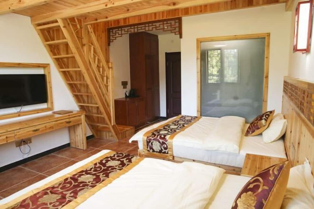 Un dormitorio con dos camas, televisión, escritorio de madera y una escalera.
