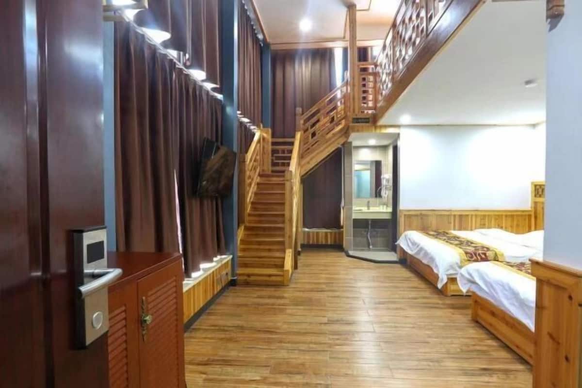 Una habitación de hotel con escalera de madera, cama, escritorio y armario.