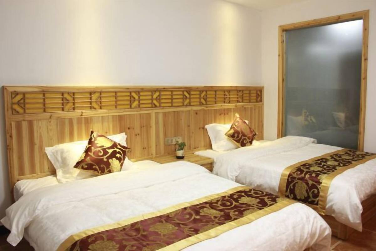 Habitación de hotel con dos camas, cabecero de madera, ropa de cama blanca y un ventanal grande.