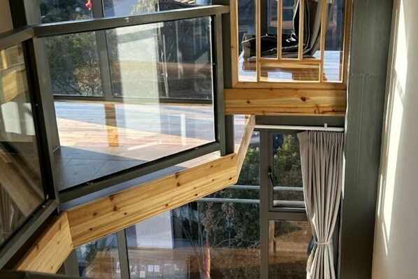 Un interior moderno con un ventanal grande, vigas de madera y una cortina.