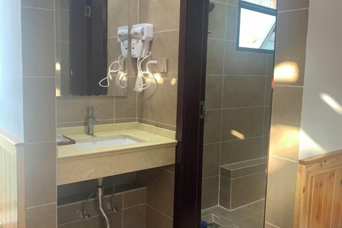 Un baño con lavamanos, dos secadores de pelo y un espejo.
