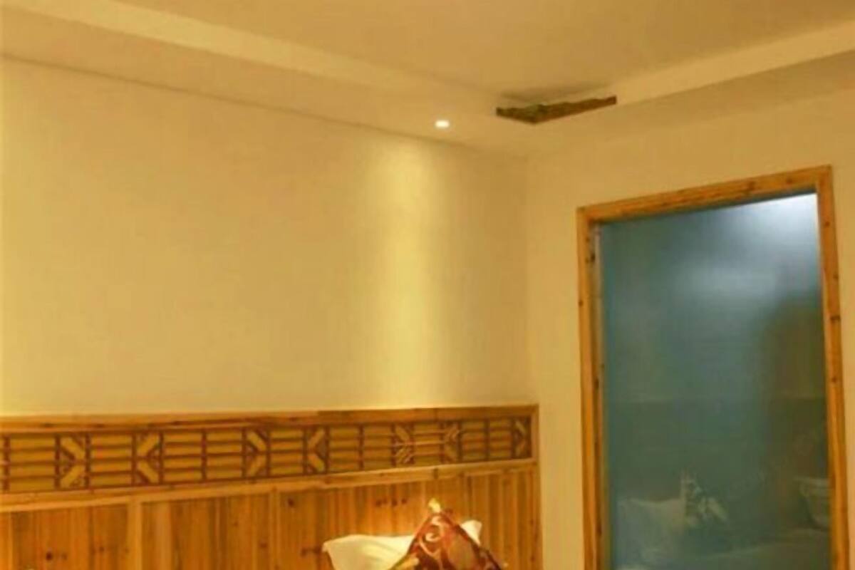 Una habitación con cabecera de madera, una cama y un ventanal grande.