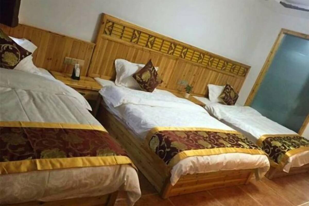 Una habitación con tres camas de madera alineadas contra la pared, cada una con cabecero y almohadas.