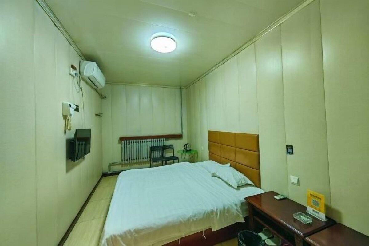 Une chambre d’hôtel équipée d’un lit, d’une petite table, d’une chaise, d’un climatiseur et d’un radiateur.