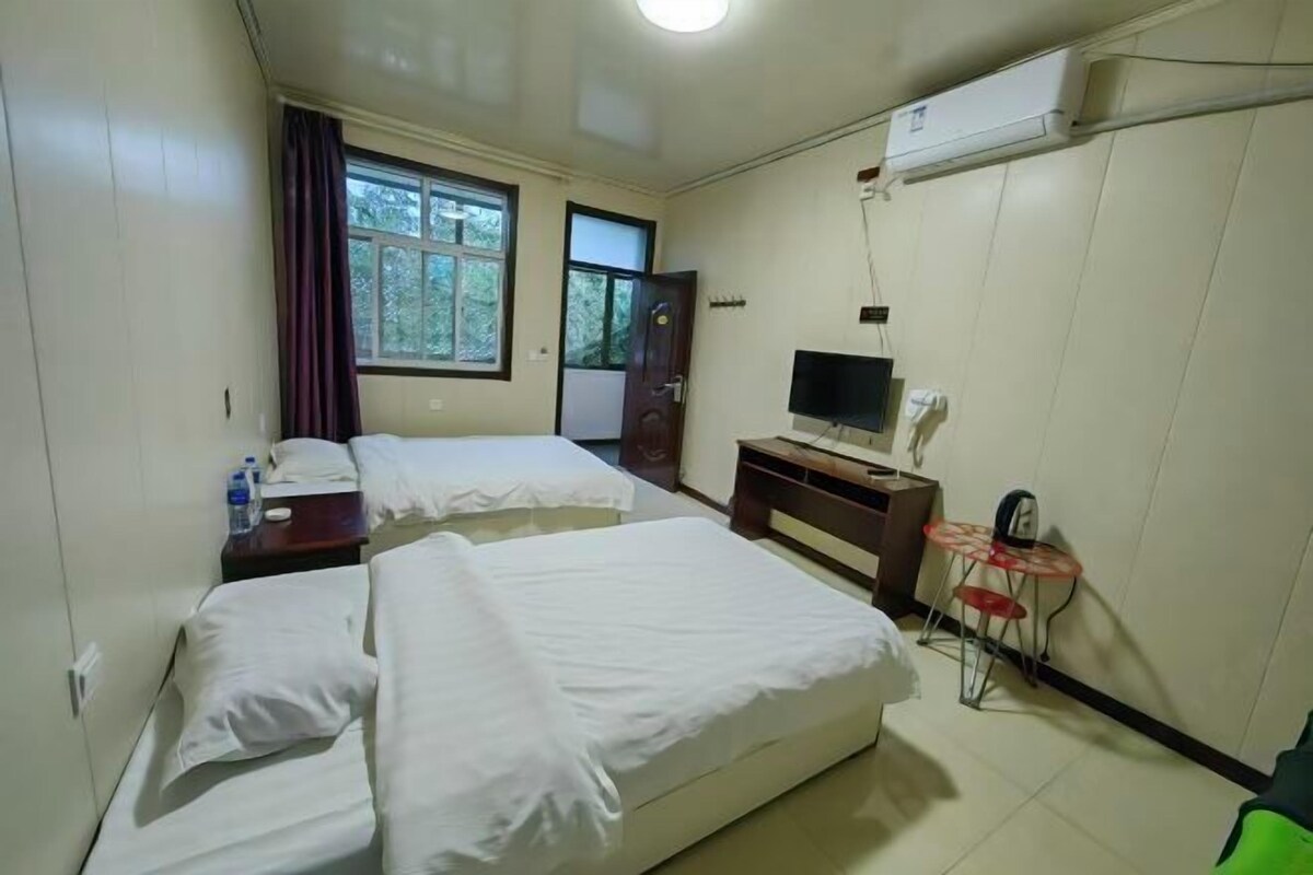 Une chambre d’hôtel avec deux lits, une télévision, une petite table et un appareil de climatisation.