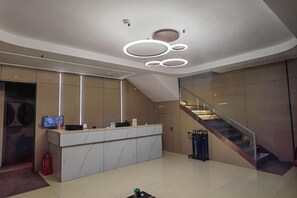 A modern reception area with a marble counter, a digital screen, and a staircase. - Binxi Hotel (Linfen Yingbin Avenue Museum Branch) (Linfen)