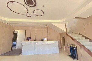 Zona de recepción con mostrador, escalera y diseño moderno en el techo.