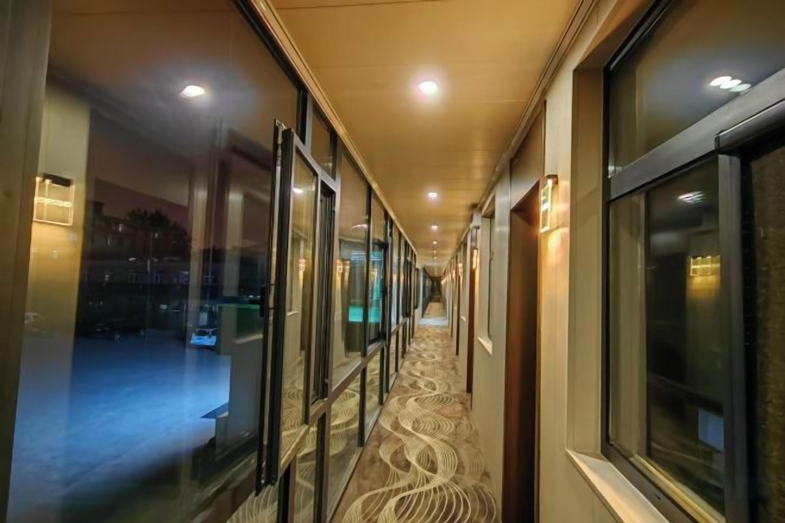 A hotel corridor with glass doors, a patterned carpet, and overhead lighting.