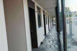 A corridor with doors leading to rooms, a patterned carpet, and a glass wall reflecting the outside. - Binxi Hotel (Linfen Yingbin Avenue Museum Branch) (Linfen)