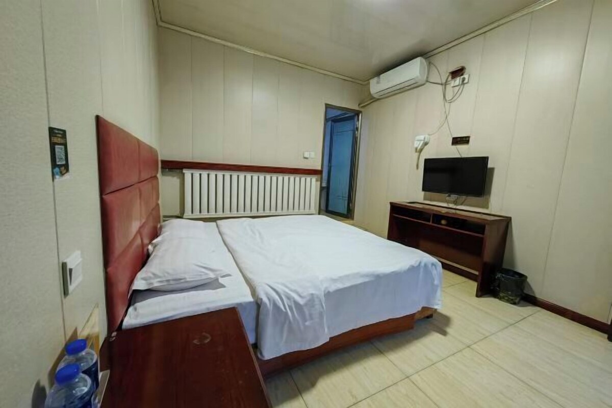 Une chambre d’hôtel équipée d’un lit, d’une télévision, d’une commode en bois et d’un appareil de climatisation.