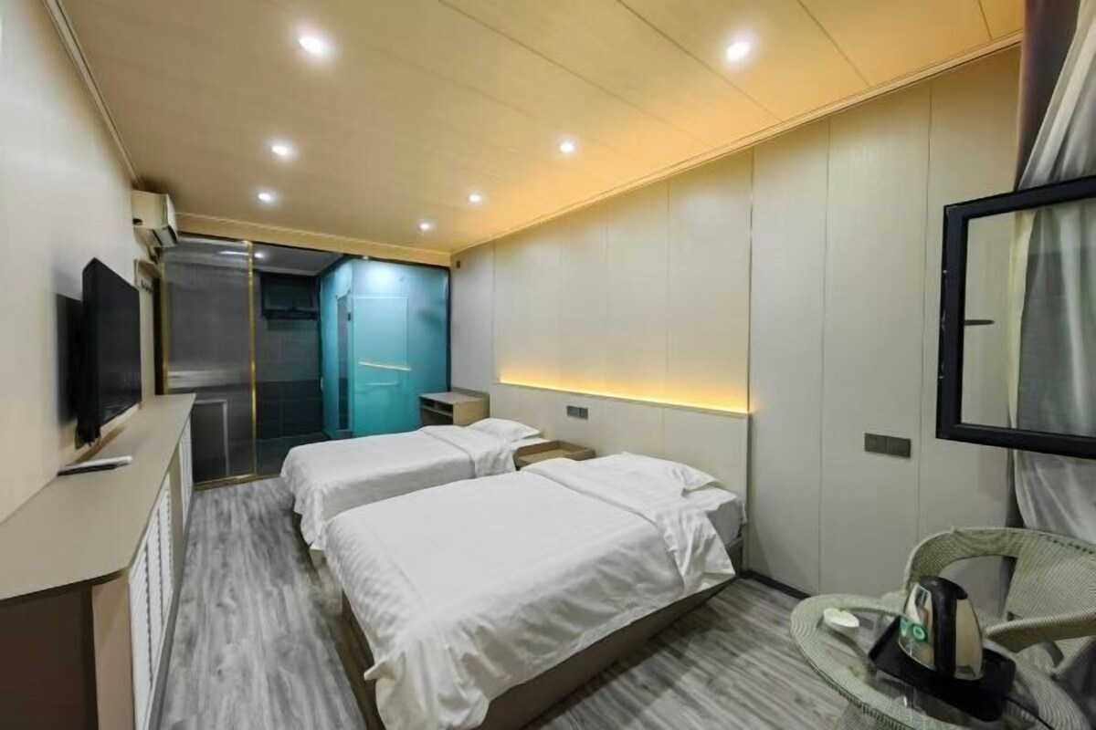 Une chambre d’hôtel avec deux lits, une télévision, un bureau, une chaise et un miroir.