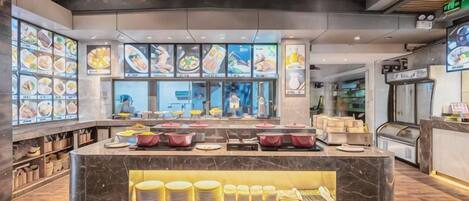 A restaurant interior with a marble counter, food display windows, and a seating area.