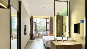 Une chambre d’hôtel avec un grand lit, une salle de bain avec un miroir et une vue sur l’extérieur.