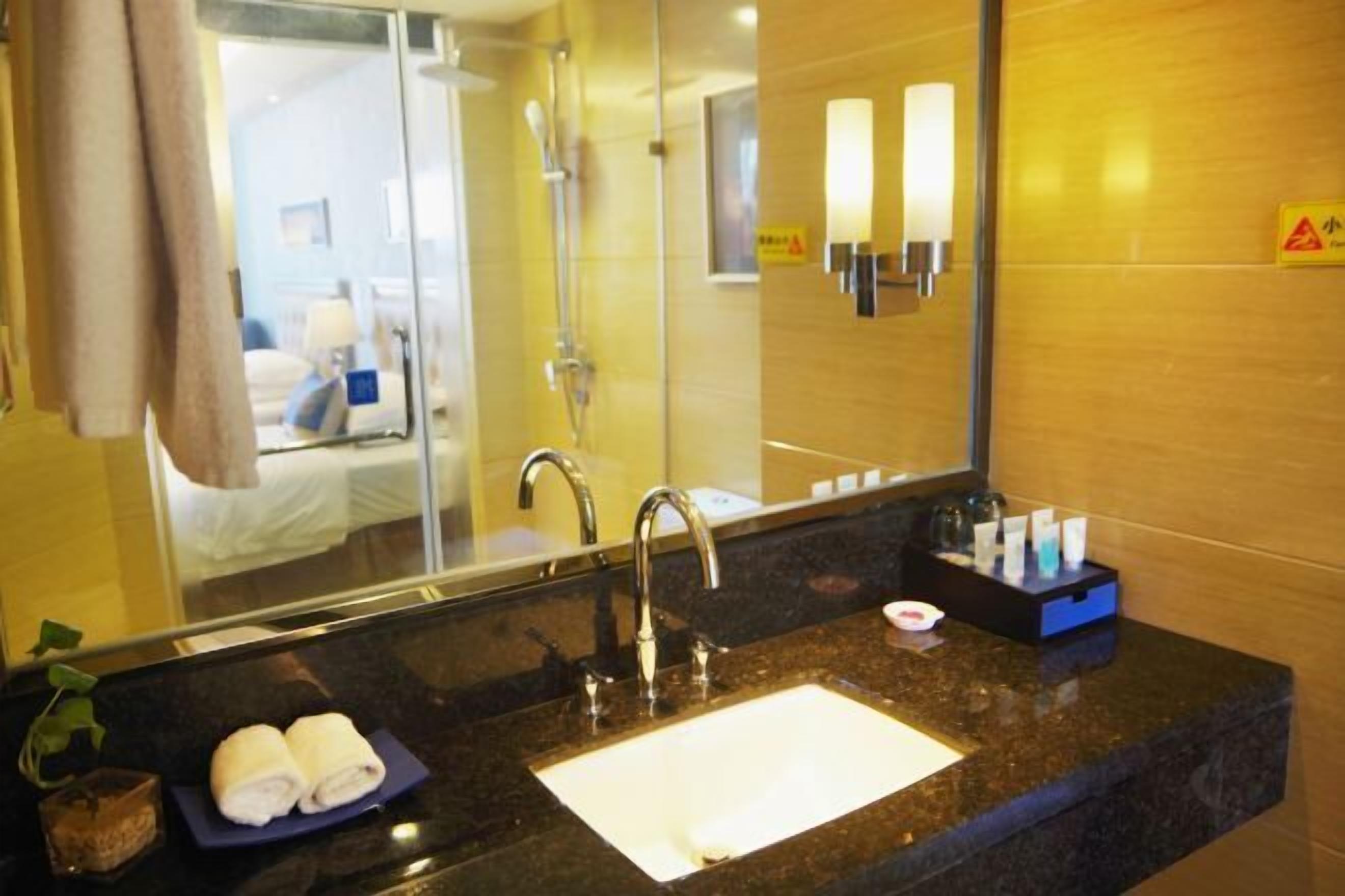 Un baño de hotel con un espejo grande, un lavamanos y un perchero para toallas.