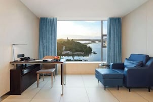 Una sala de estar moderna con un escritorio, un sofá azul y vista a un cuerpo de agua.