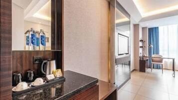 Un baño de hotel moderno con encimera de granito, un espejo grande y una estación de café.