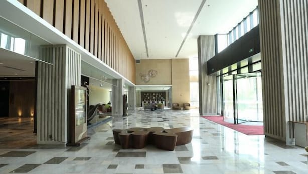 Un hall d’entrée spacieux, doté d’un sol à carreaux, d’un espace salon central et de grandes fenêtres sur un côté.