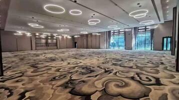 A large conference room with a patterned carpet, recessed ceiling lights, and large windows.