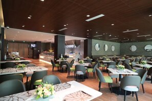 Un restaurant moderne doté de plusieurs tables et chaises, d’un bar et d’une cuisine située à l’arrière.