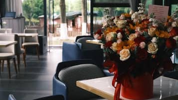 A dining area with tables and chairs, a vase of flowers, and a menu sign.
