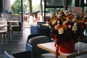 Un espace repas avec des tables et des chaises, un vase de fleurs et un panneau affichant le menu.